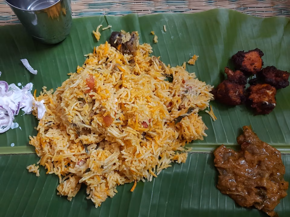Chicken biryani served on banana leaf with sides
