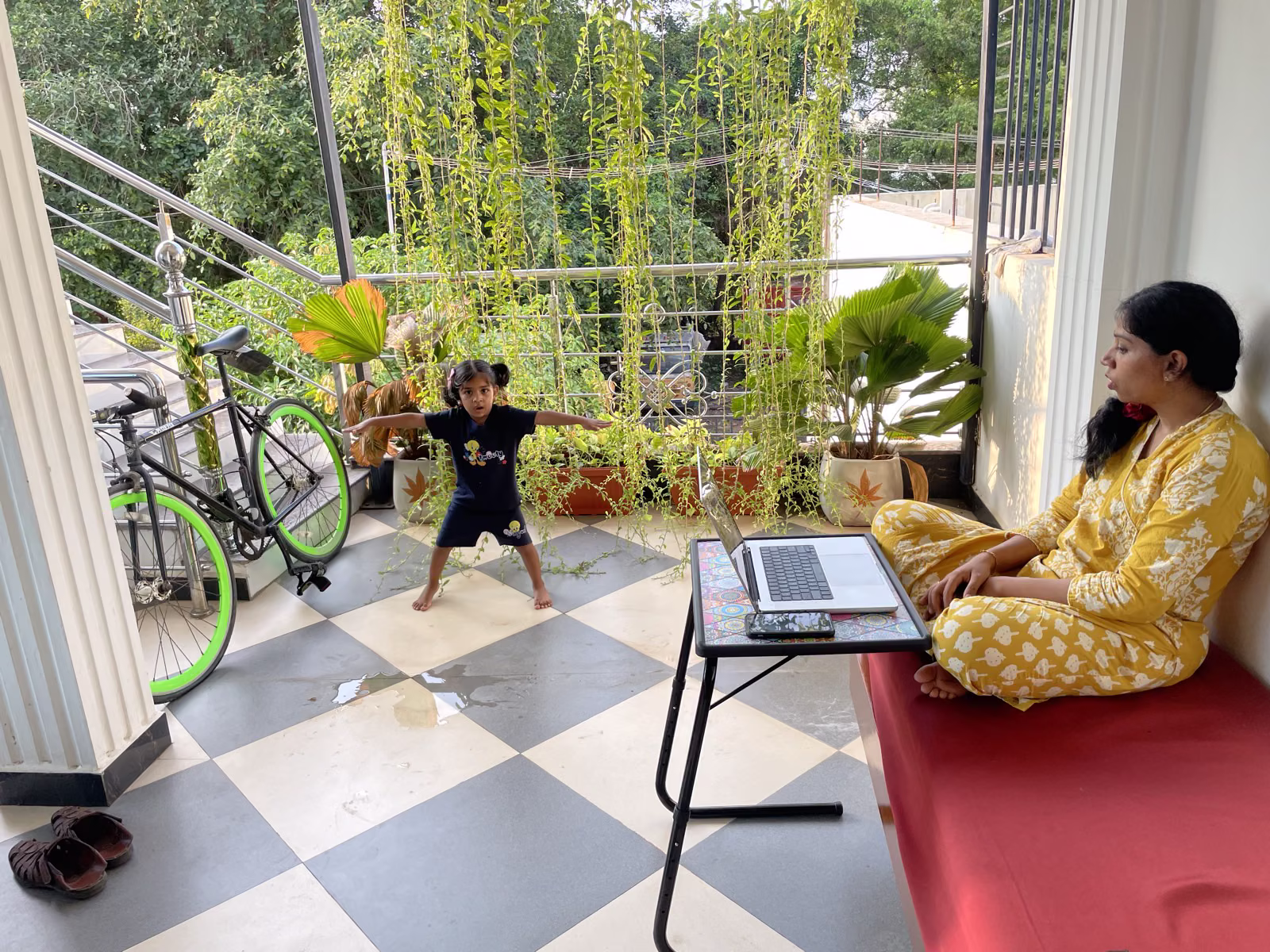Vine-draped balcony at Nivaa Stays — laptop on adjustable stand, slow afternoons between calls